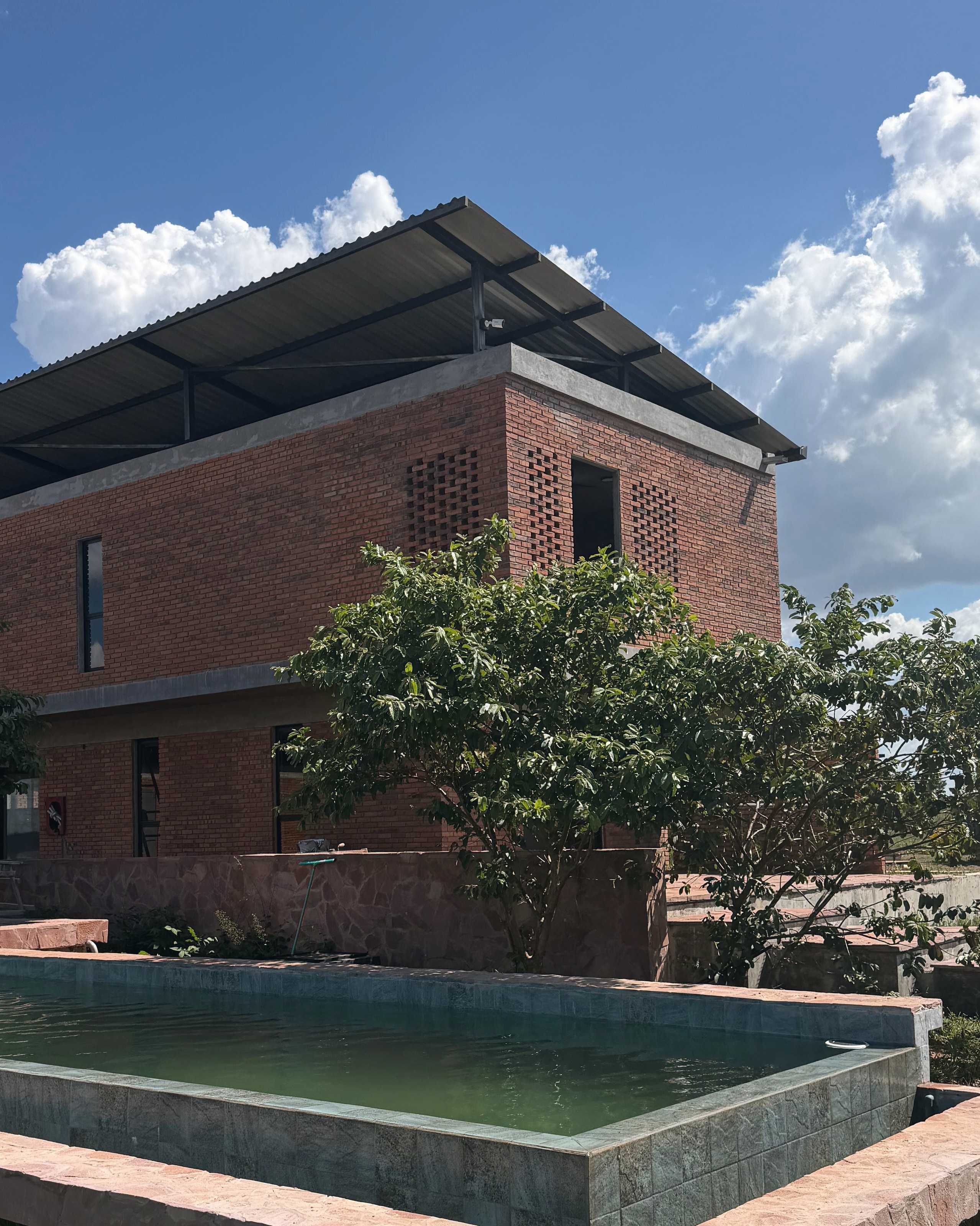 The exposed-brick building with lattice walls, beside the green-water pool with its pink stone edge.