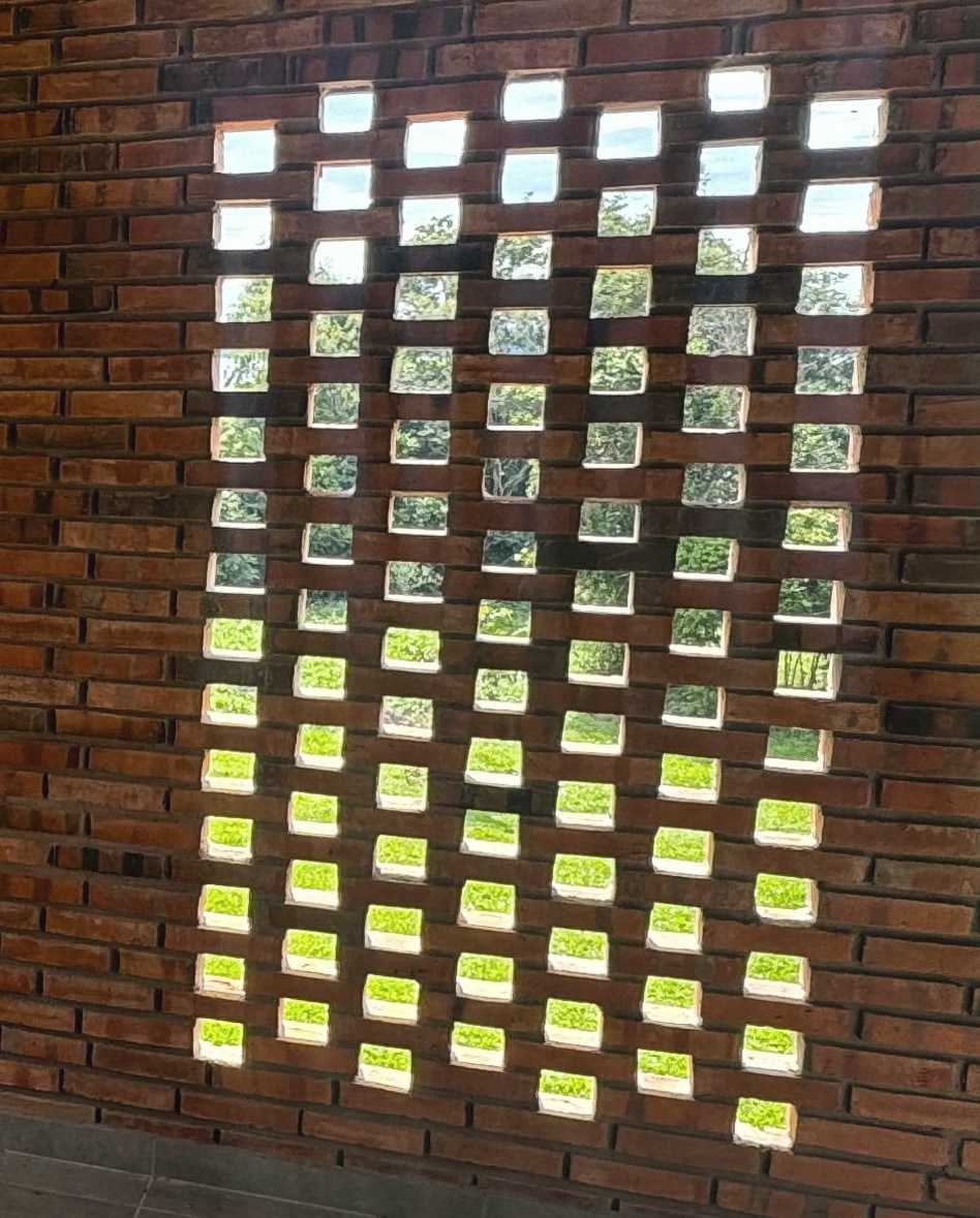 A brick lattice wall with daylight coming in through its openings.